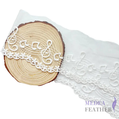 Black and off-white tulle lace trim with embroidered music note patterns. - White